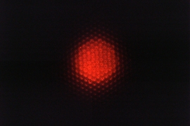 This optical micrograph of the inside of a luminescent substrate shows the red fluorescent emission from the quantum dot layer on top of the micropatterned bottom reflector. 