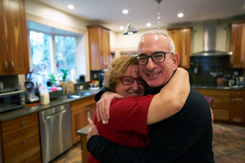 Joshua Angrist hugs his wife, Mira Angrist, in their kitchen