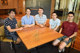 Photo of five men posing around a table with a 3D model on the table.