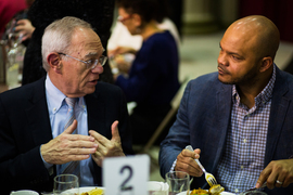 Rafael Reif talking with a colleague at a table during a conference