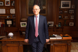 Rafael Reif stands in front of his desk in his MIT office