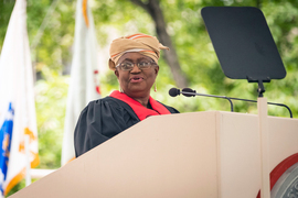 MIT Commencement speaker Ngozi Okonjo-Iweala stands at the podium, with flags in the background.