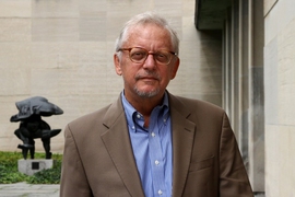 Portrait headshot of John Tirman, posing in a courtyard