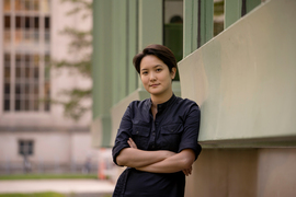 Photo of Jamie Wong outside and learning against the façade of Hayden Memorial Library. Background is windows and beige and dusty green walls.
