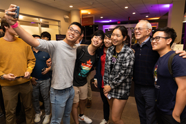 Indoor photo of five MIT students taking a selfie with MIT President L. Rafael Reif