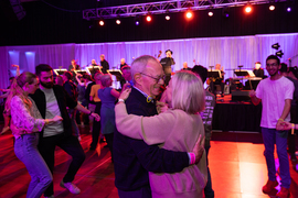 L. Rafael Reif and Christine Reif embrace in dance as others around them dance and play music
