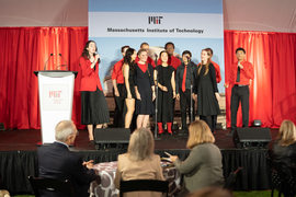 The Chorallaries, made up of about ten students, perform on stage in front of a red and white backdrop