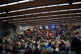Students in a busy auditorium wait for the movie to start.