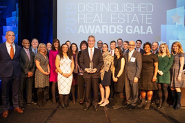 Group photo of Steve Marsh, in center holding an award, on stage and surrounded by about 20 people.