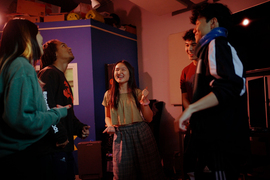 Ji, in the center, sings with 4 people in a practice studio.