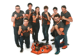 The Tantrum team poses with their fists in a fighting stance with their orange and black robot in the center. They are wearing orange and gray shirts that have "Tantrum" printed on them.