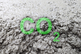 Green bold letters say “CO2” with wet cement in background.