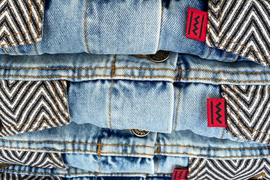 Closeup of blue jeans and striped fabric, with red Congo Clothing logos.
