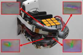 Photo shows a robotic hand holding a Rubik's Cube. Four insets shows colorful renderings of the hand’s sensors. 