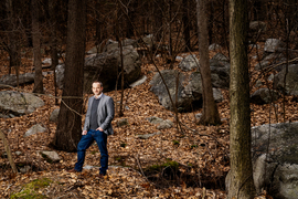 A wide-angle shot shows the beautiful brown woods and fallen leaves around Fournier, who stands on the left side with hand in pocket.