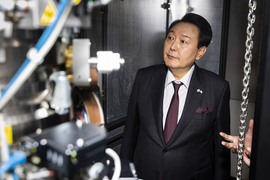 President Yoon Suk Yeol looks at a large device, which is out-of-focus in the foreground. 