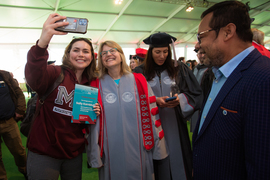A woman wearing an MIT shirt takes a selfie with Kornbluth while inside the busy ceremony tent.
