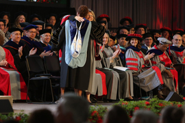 Sally Kornbluth hugs Valerie Sheares Ashby as faculty in background clap.