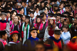 A crowded scene of MIT graduates smiling while in graduate regalia. Many wear colorful sashes.