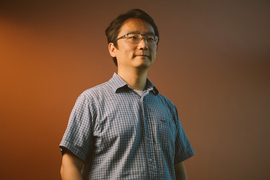 Andy Sun poses for portrait while facing slightly left against a gradient tan background.