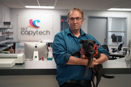 In Copytech, Scott holds his black dog, Holly.