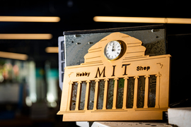 A laser-cut Great Dome made of wood has a clock and says, “MIT Hobby Shop.”
