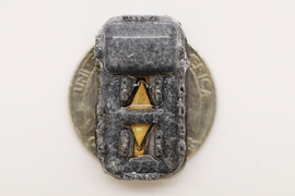 The tiny device fits on a quarter. The diamond-shaped piece of material is visible, but the rest of the device is covered in gray fibers.