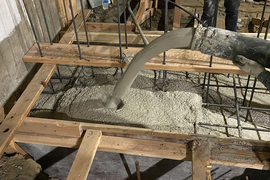 Concrete is being poured in a building, with wood and rebar.