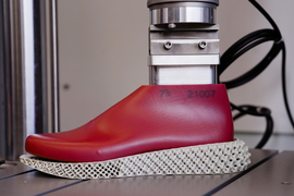 A red 3D printed shoe sole on a testing machine