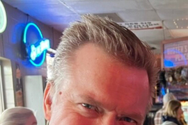 Photo of Casey Harrington smiling while at a restaurant.