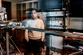 Rafael Jaramillo in the lab surrounded by racks of equipment. There is an artistic blur to the image, creating movement.