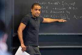 Isaiah Andrews teaching at an equation-covered blackboard