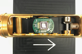 The gold cylindrical device has a circuit board and gears inside. 