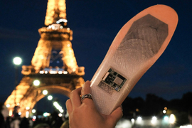 A prototype of the sole is held up, with the Eiffel Tower in background.