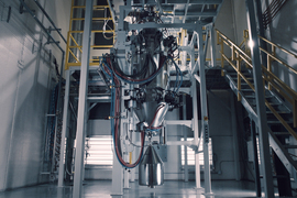 A large, tall, cylindrical machine with a pointy end, in a clean lab.