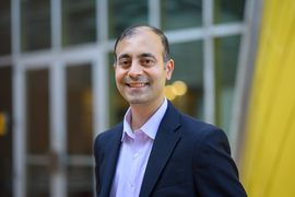 Rohit Karnik stands in front of a building with windows and a yellow wall