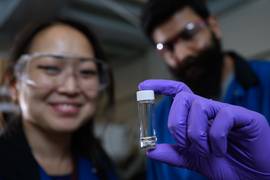 A researcher holds a vial of liquid molten sodium metal.