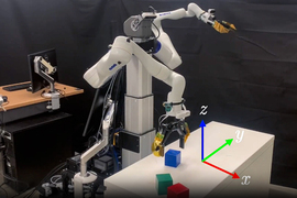 A robot arm with three different colored blocks in front of it