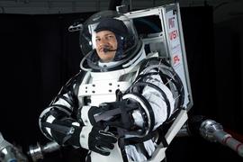 Erik Ballesteros wears a large astronaut suit with thick arms.