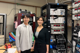 Shuwen Sun and Jeong Min Park stand in front of large scientific equipment in a lab