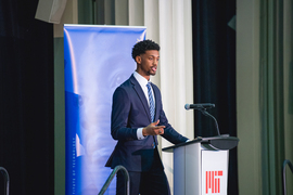 Michael Ewing speaks at a lectern 