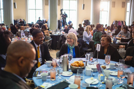 Sally Kornbluth, Paula Hammond, and others chat at a round table with other tables in the background