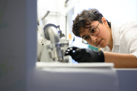 Palak Patel leans on a lab bench, examining something out of the camera’s focus