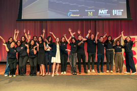 About 20 people on stage raise their hands in glee.
