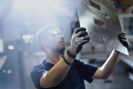 A worker looks at a sheet of steel.
