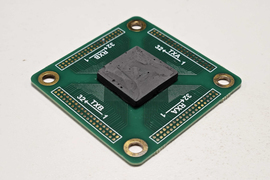 A square circuit board with black backing layer.
