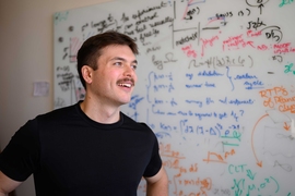 Perrin Davidson in front of a whiteboard filled with scientific equations