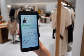 A person looking at the Cartesian Systems app while in a clothing store