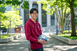 Henry Wang portrait on MIT campus while holding soccer ball.