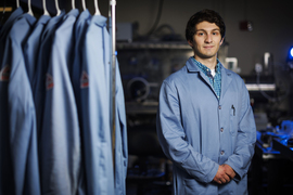 Hugh Smith stands in the lab next to lab coats.